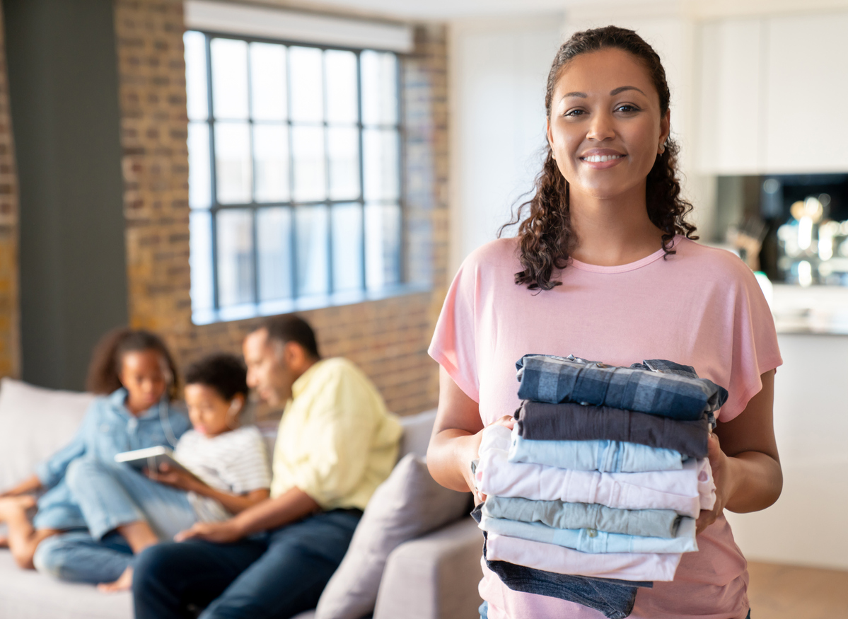 mother doing the laundry at home and looking at the camera smiling with her family