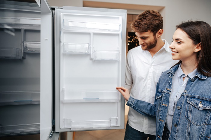 Young couple selecting a new refrigerator in household appliance store. 