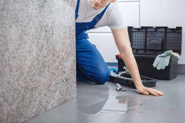 repairman checking leaking dishwasher