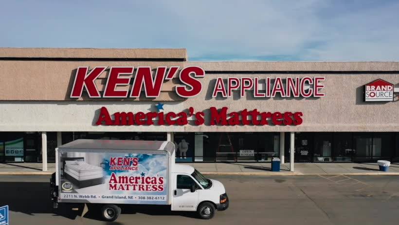 A truck driving past a Ken’s Appliance store 