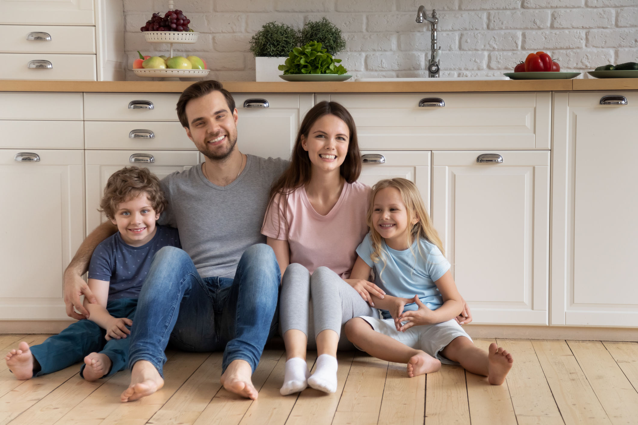 family sitting on the kitchen floor smiling