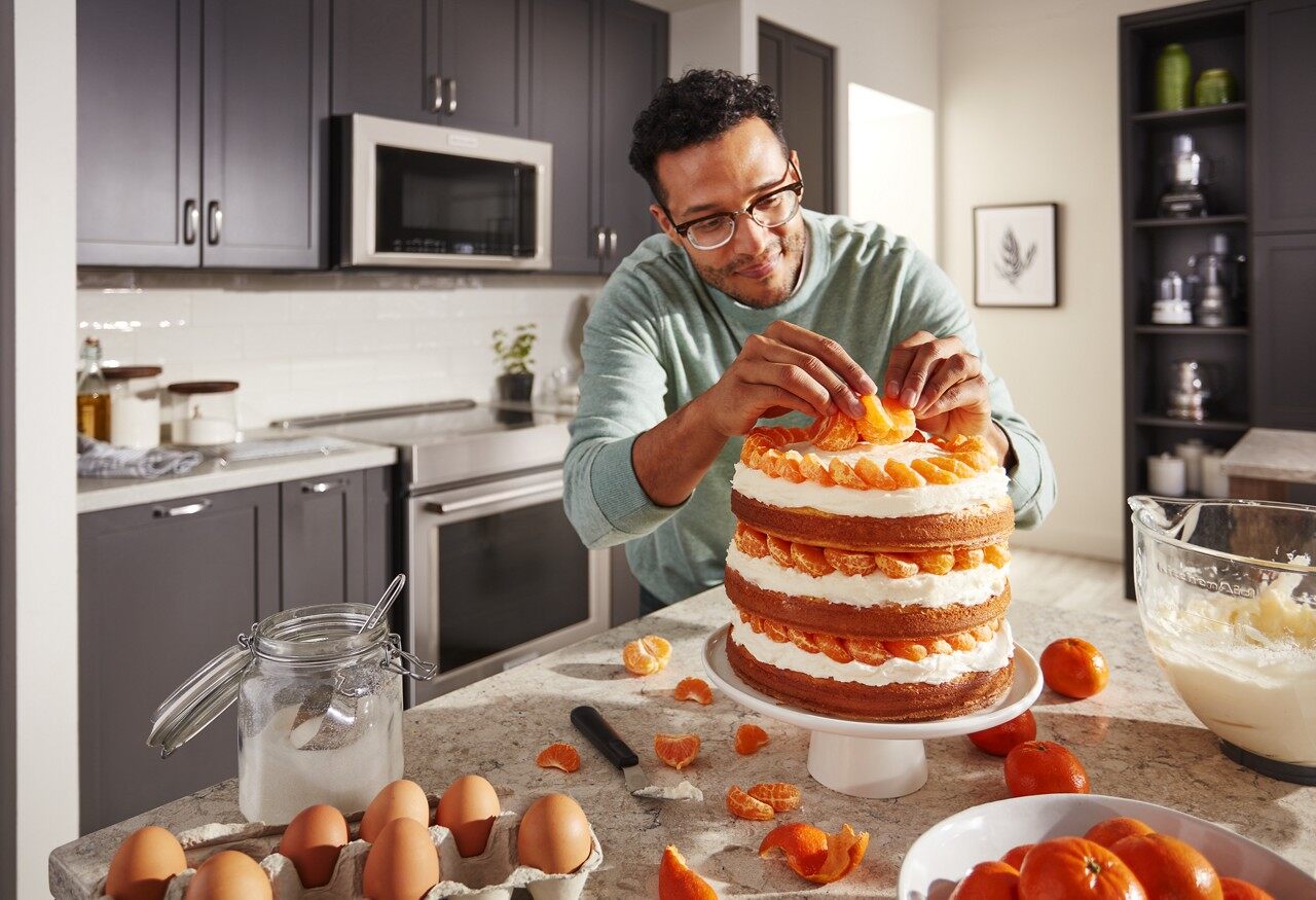 man putting finishing touches on a cake