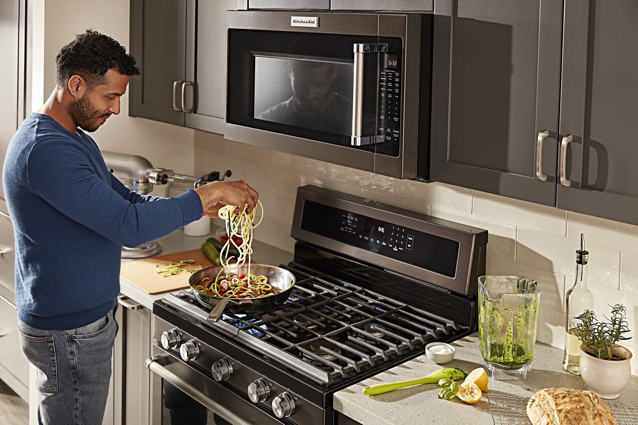 man making homemade pesto pasta on KitchenAid appliance