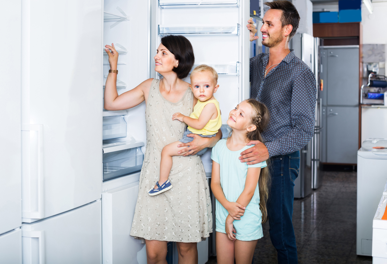 A family inspects a refrigerator in an appliance showroom.