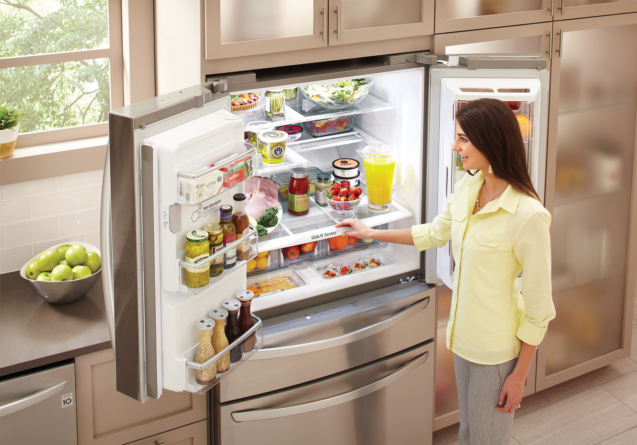 young woman retrieves food from LG stainless steel French door refrigerator