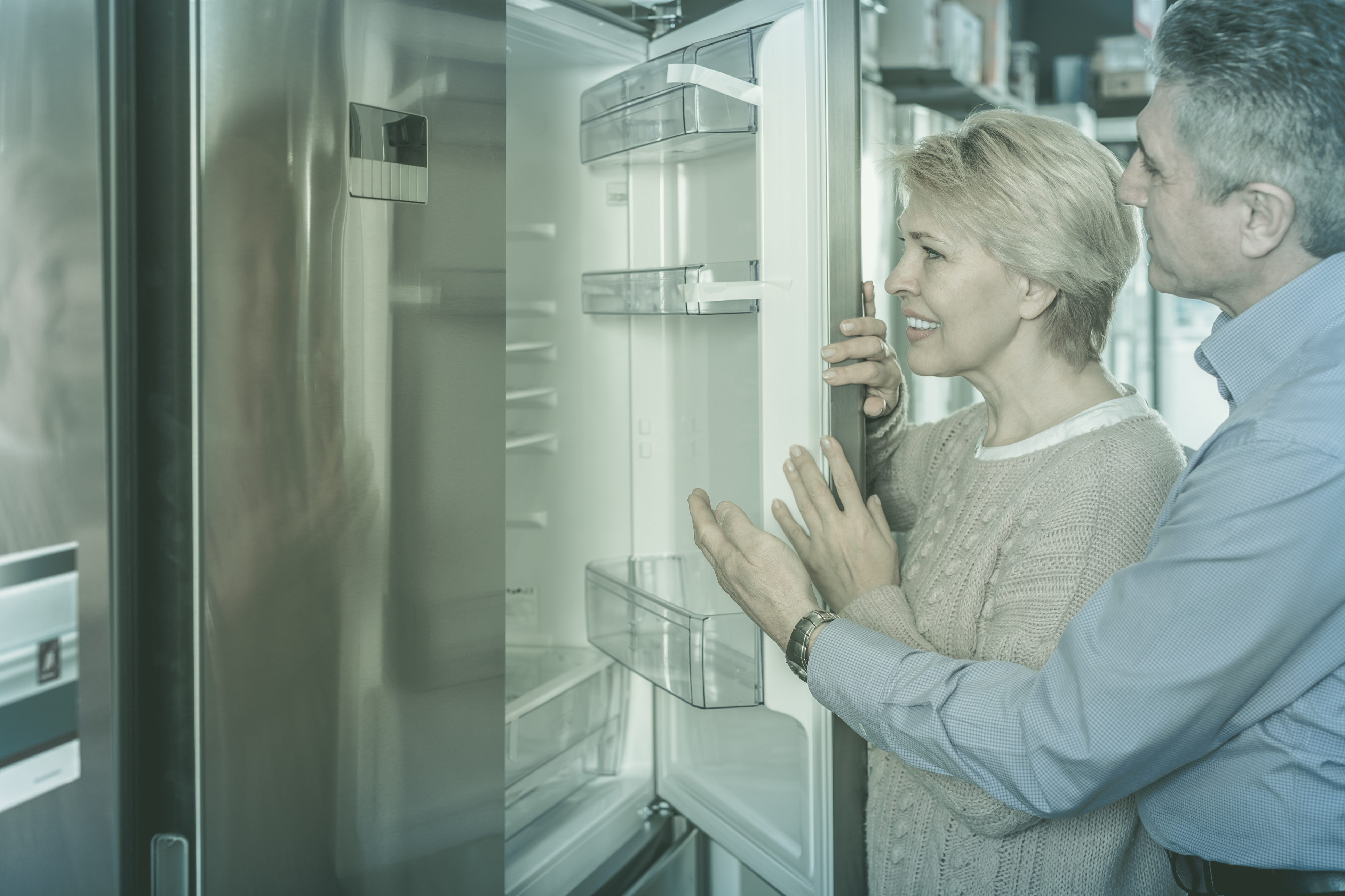 An appliance salesman showing a French door refrigerator to a woman 