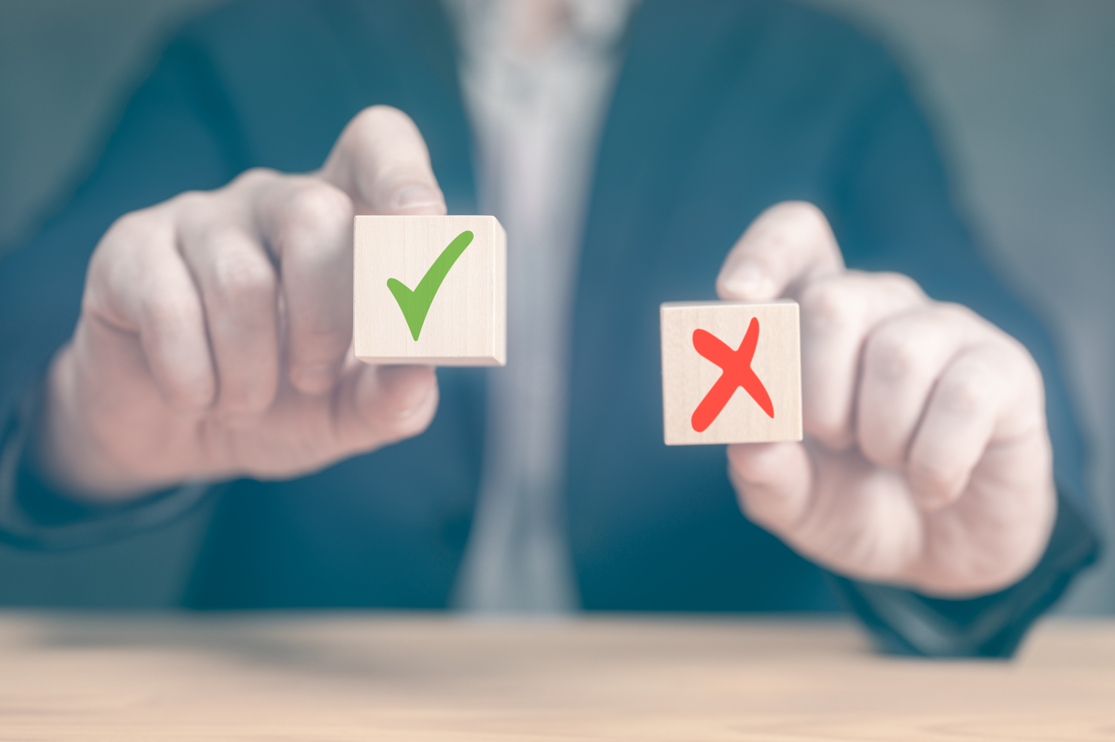 A person holding blocks with a checkmark and red X