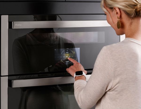 A woman selecting cooking settings on the GE Profile PTS9200SNSS double speed oven
