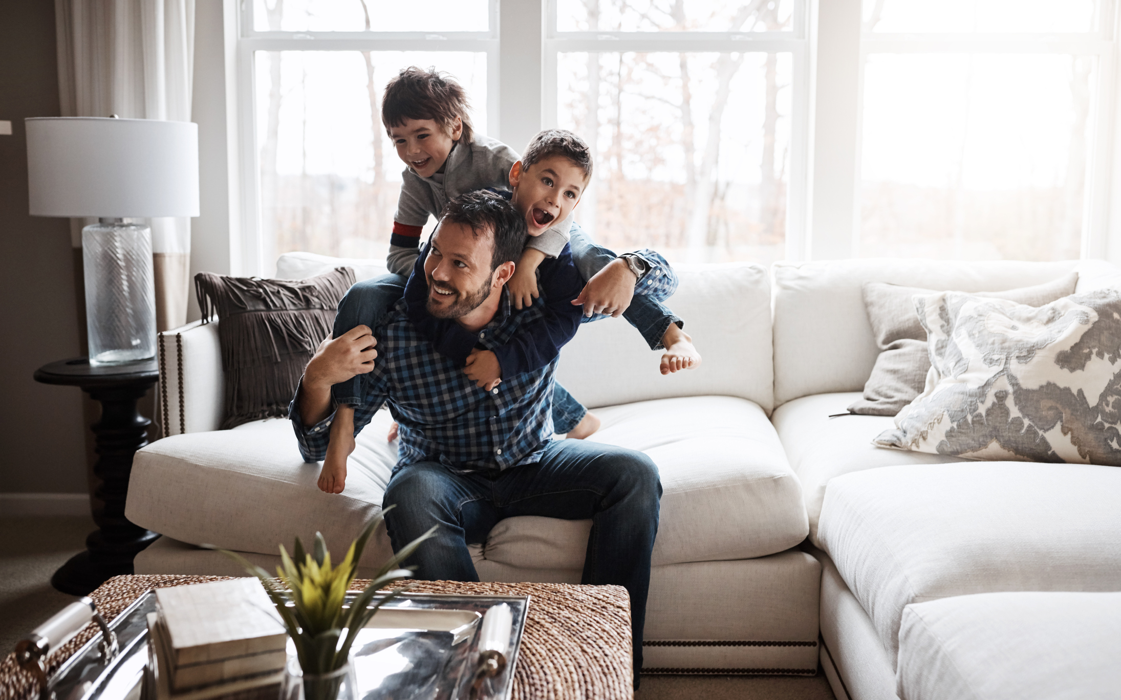 Father and sons playing on sofa in living room 
