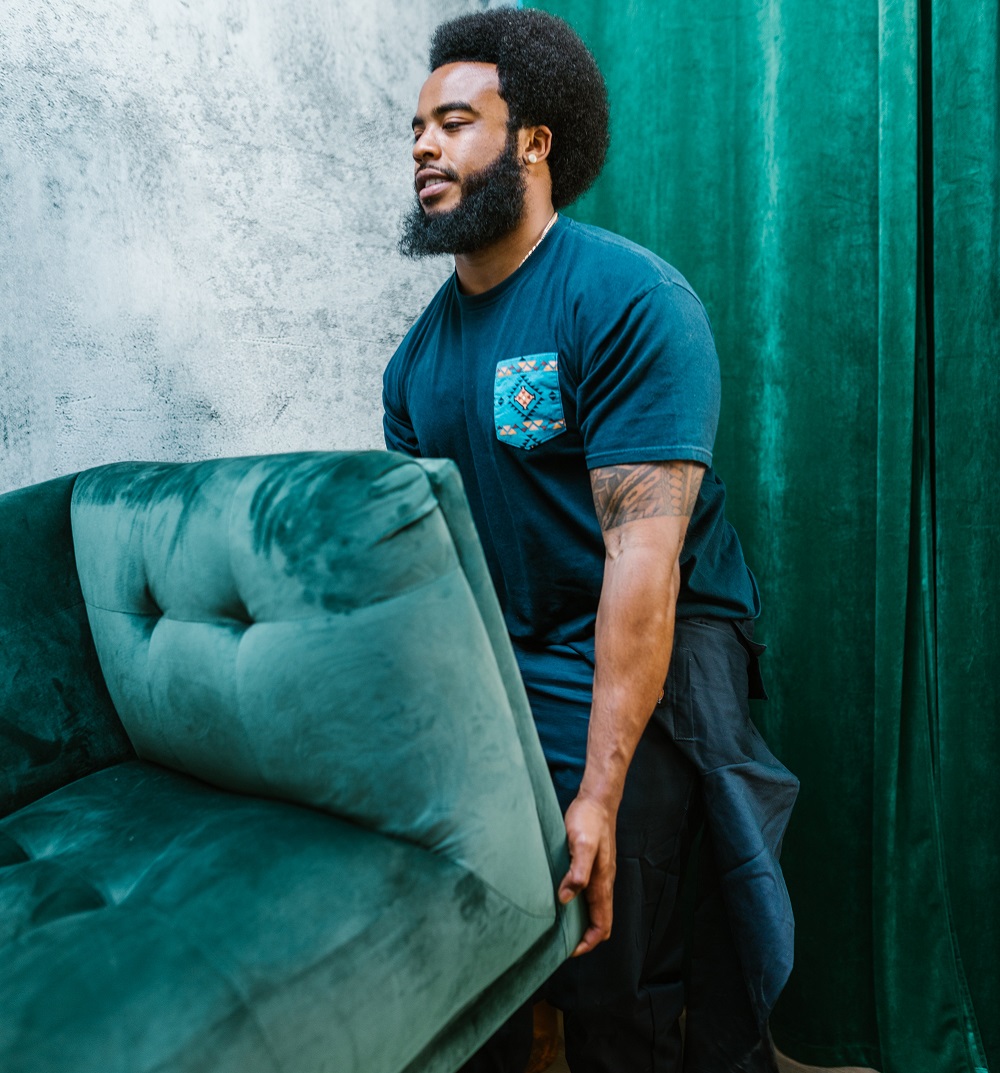 Young man moving a teal blue sofa 