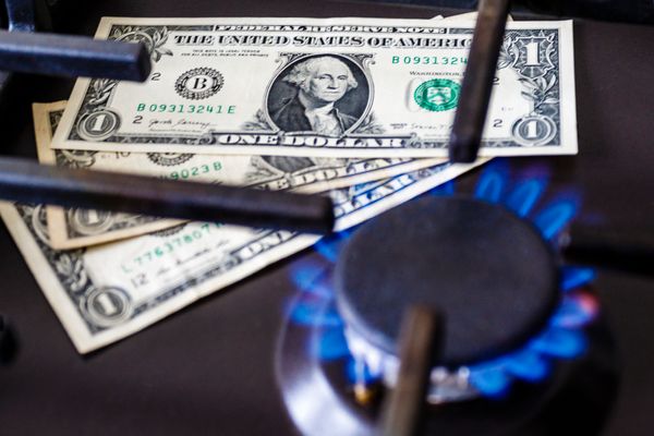 Three dollar bills beneath a gas burner that’s ignited 