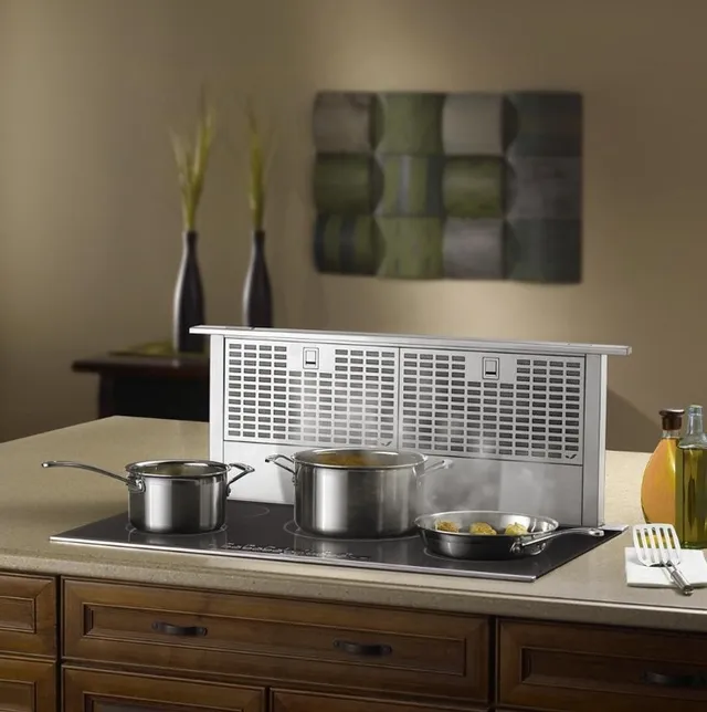 The JennAir JXD7036YS downdraft range hood in a kitchen with cookware on a cooktop 