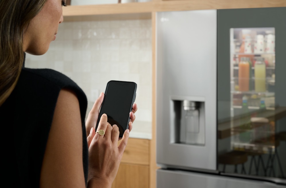 A woman using the LG ThinQ feature on an LG smart refrigerator 