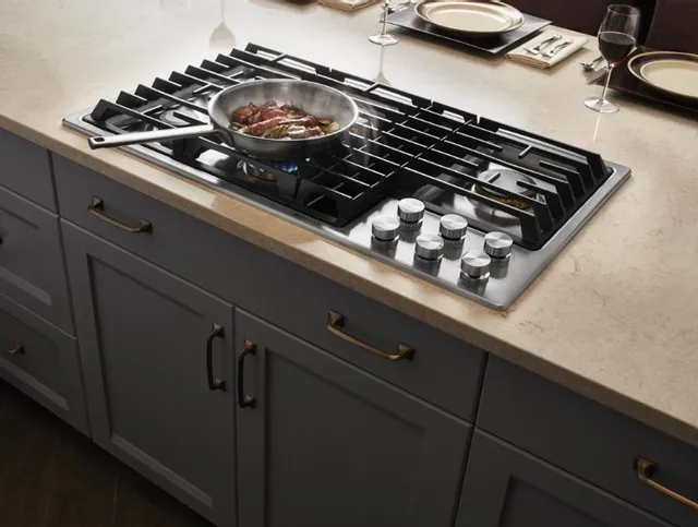 The JennAir JGD3536GS downdraft cooktop with a pan cooking and the ventilation pulling away smoke 
