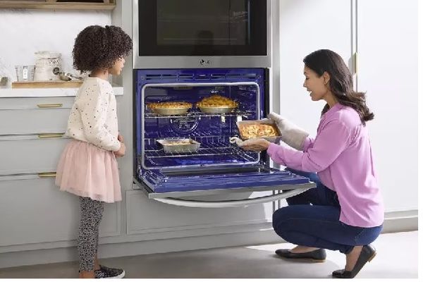 A mother and a daughter cooking various pastries inside the LG WDEP9427F oven 