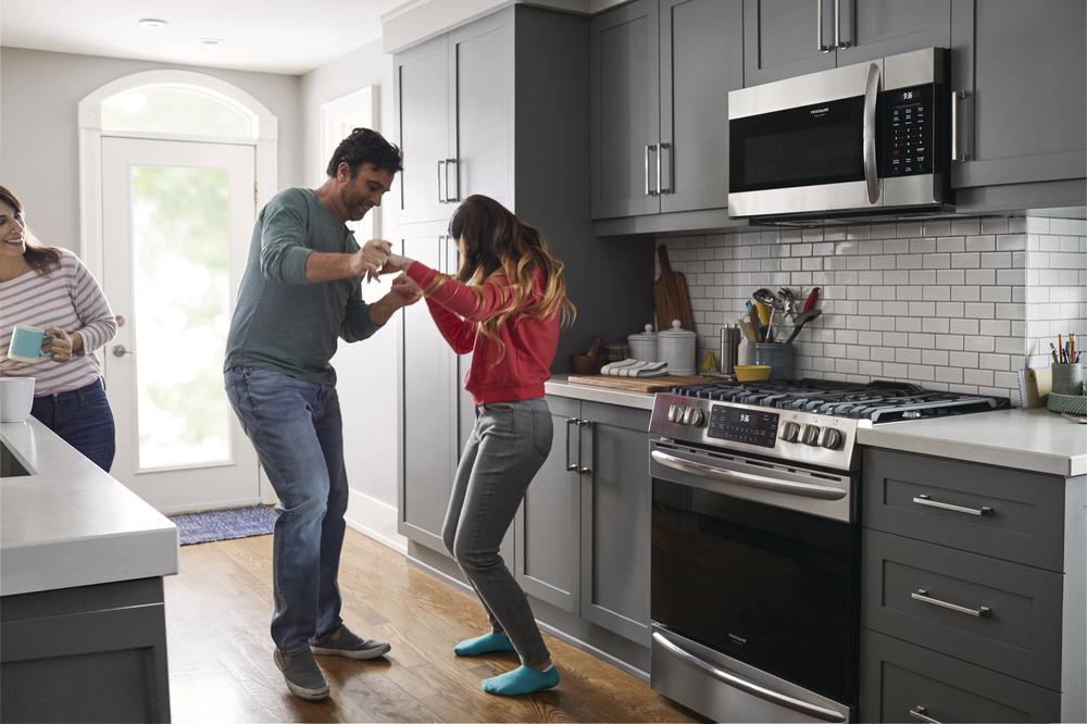 couple dances in their kitchen next to their Frigidaire Gallery slide-in range