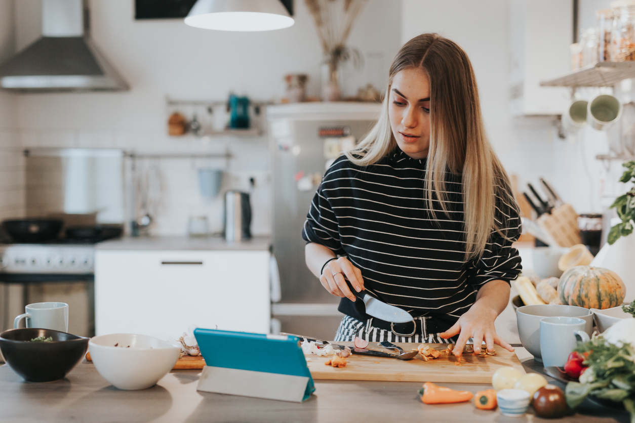 Young woman cooks using a recipe management app