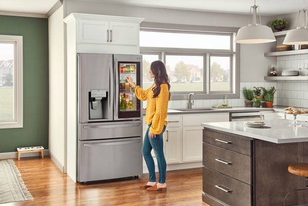 A woman checks the smart screen on her cabinet depth refrigerator