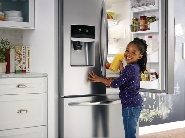 A smiling girl grabbing an item from an Electrolux refrigerator