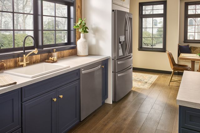 side view of a modern kitchen with dark blue cabinets and a counter depth refrigerator
