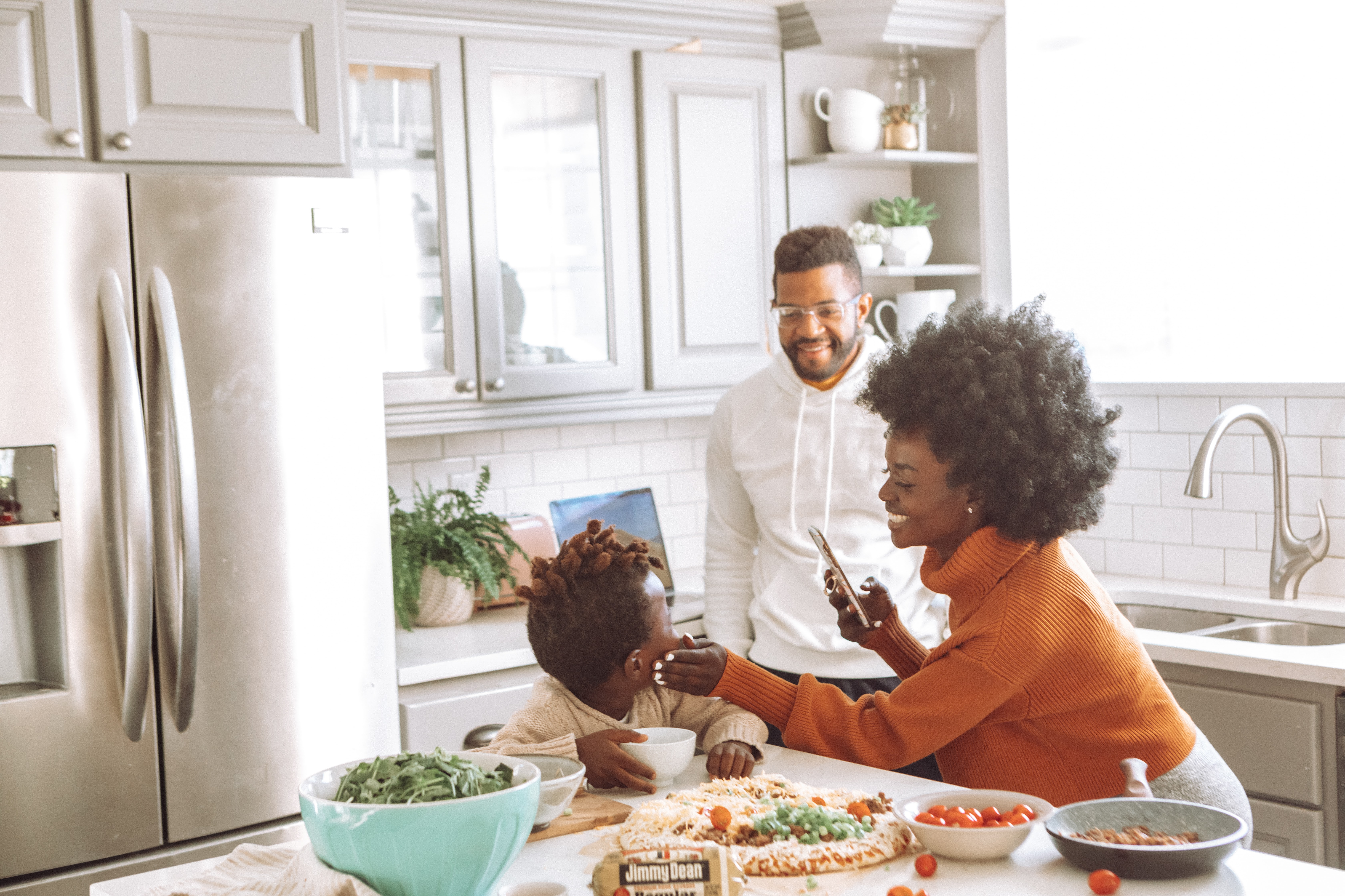 family hangs out in kitchen next to their stainless steel French door refrigerator