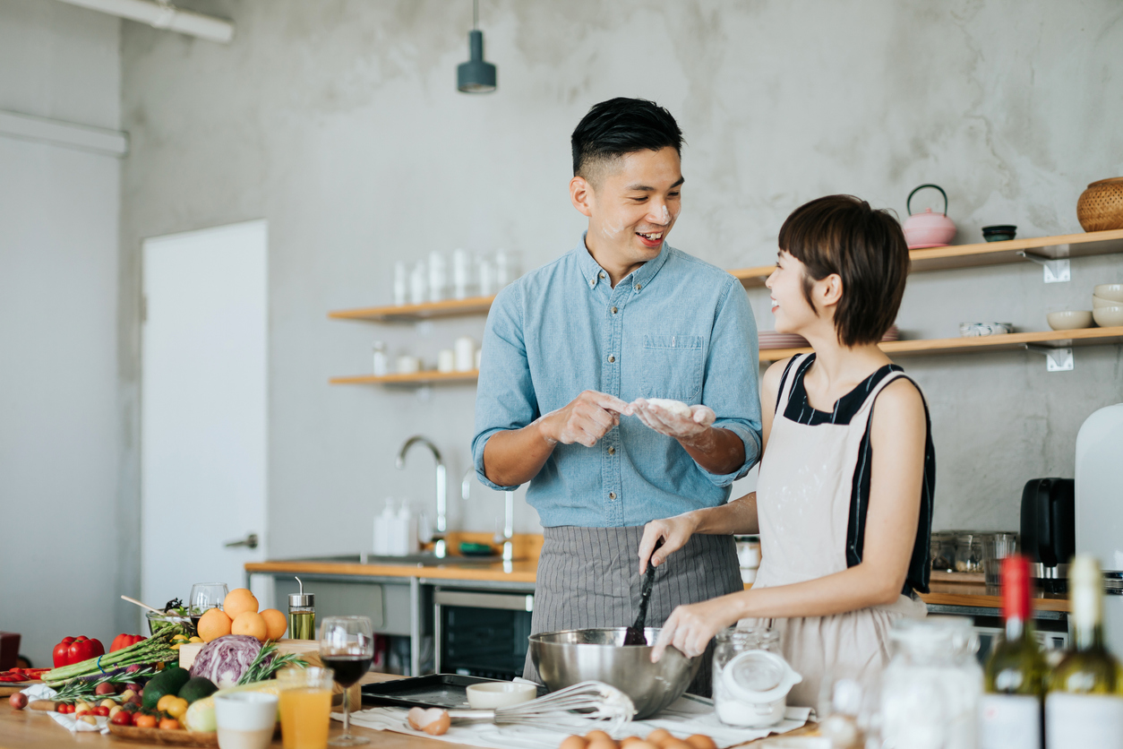 Asian man and woman prepare food together in a kitchen