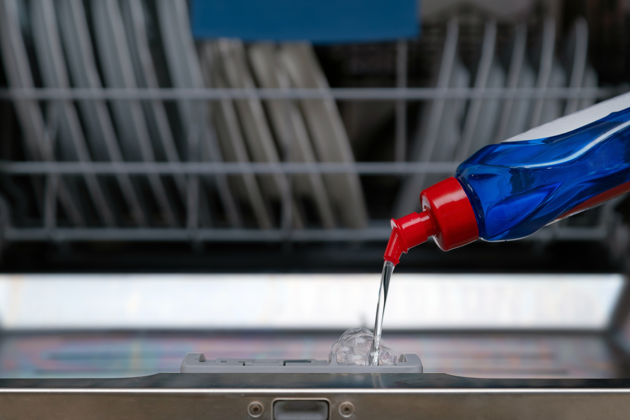 closeup of liquid soap pouring into dishwasher in the kitchen
