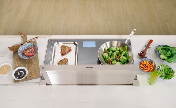 A Thermador induction cooktop featured with ingredients and a downdraft range hood