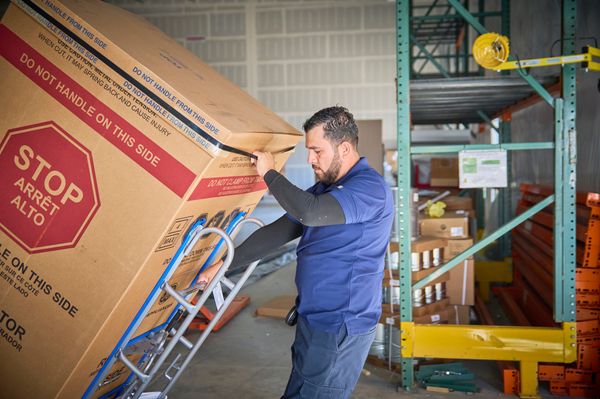 A delivery man hauling an appliance out of a warehouse 