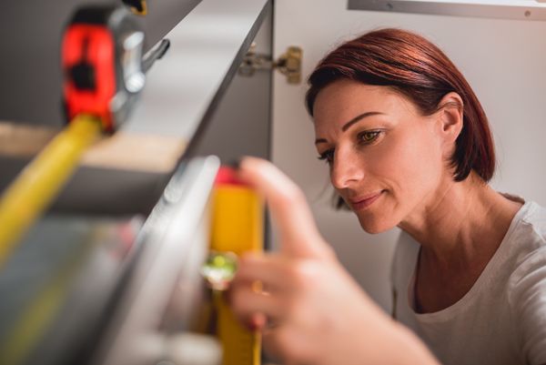 A woman using a level in the kitchen
