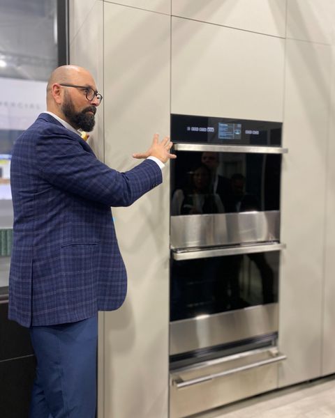 A salesman demonstrating a high-end double wall oven