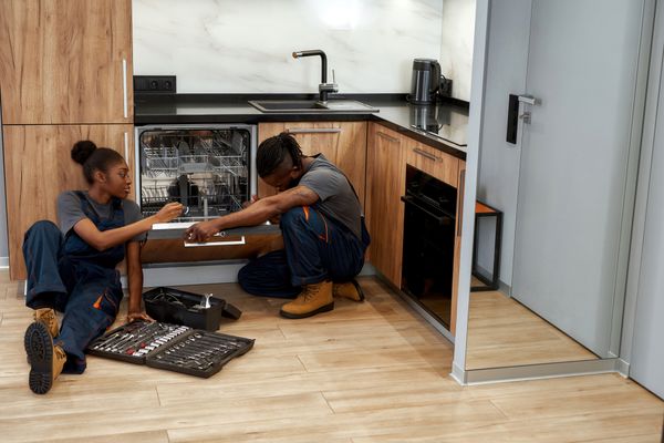 A man and a woman assembling a panel ready dishwasher 