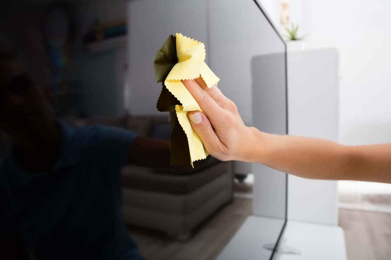 Closeup of person cleaning a flat screen TV with a microfiber cloth 