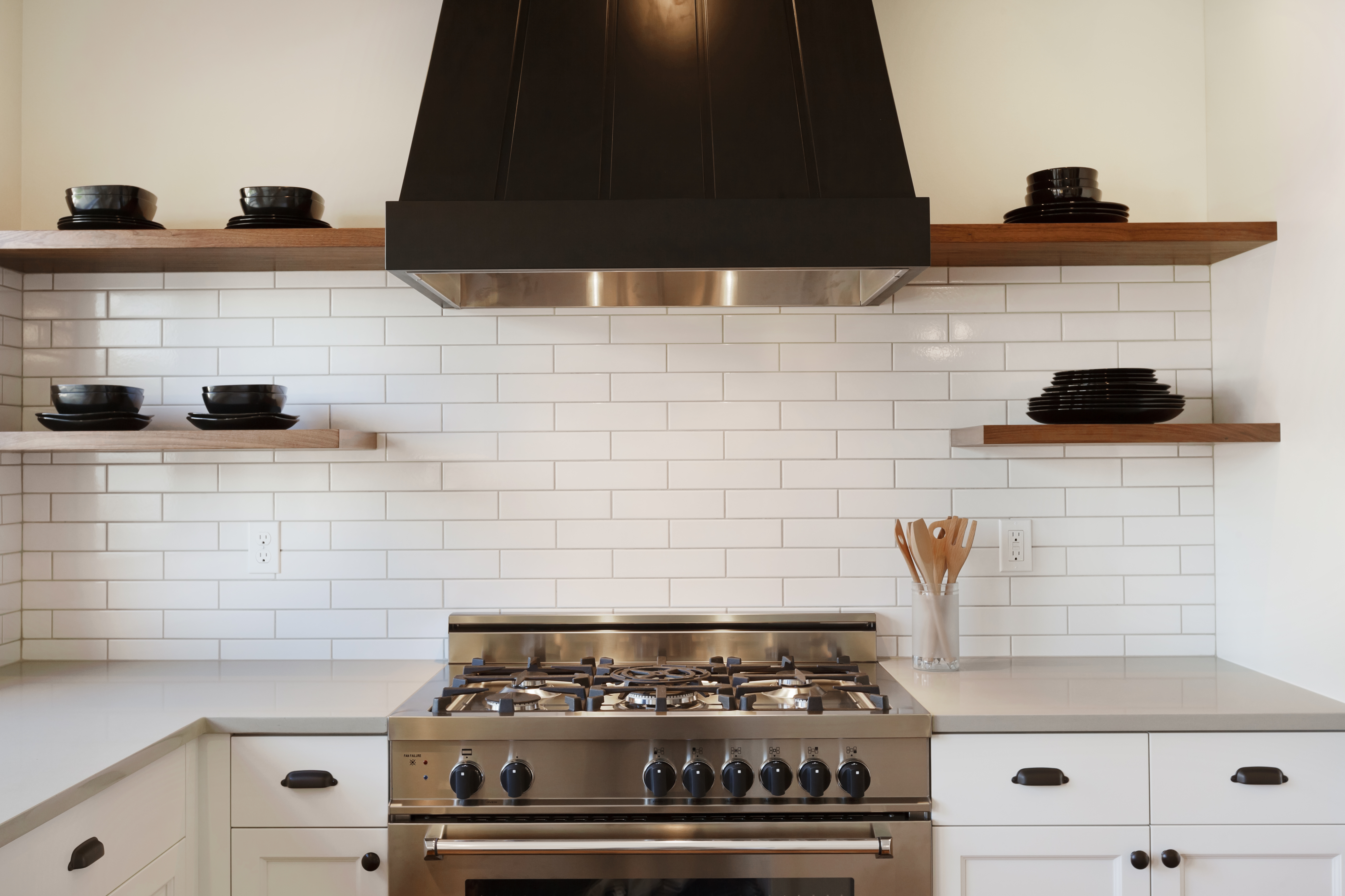 A pro-style range with custom hood installed before subway tile 