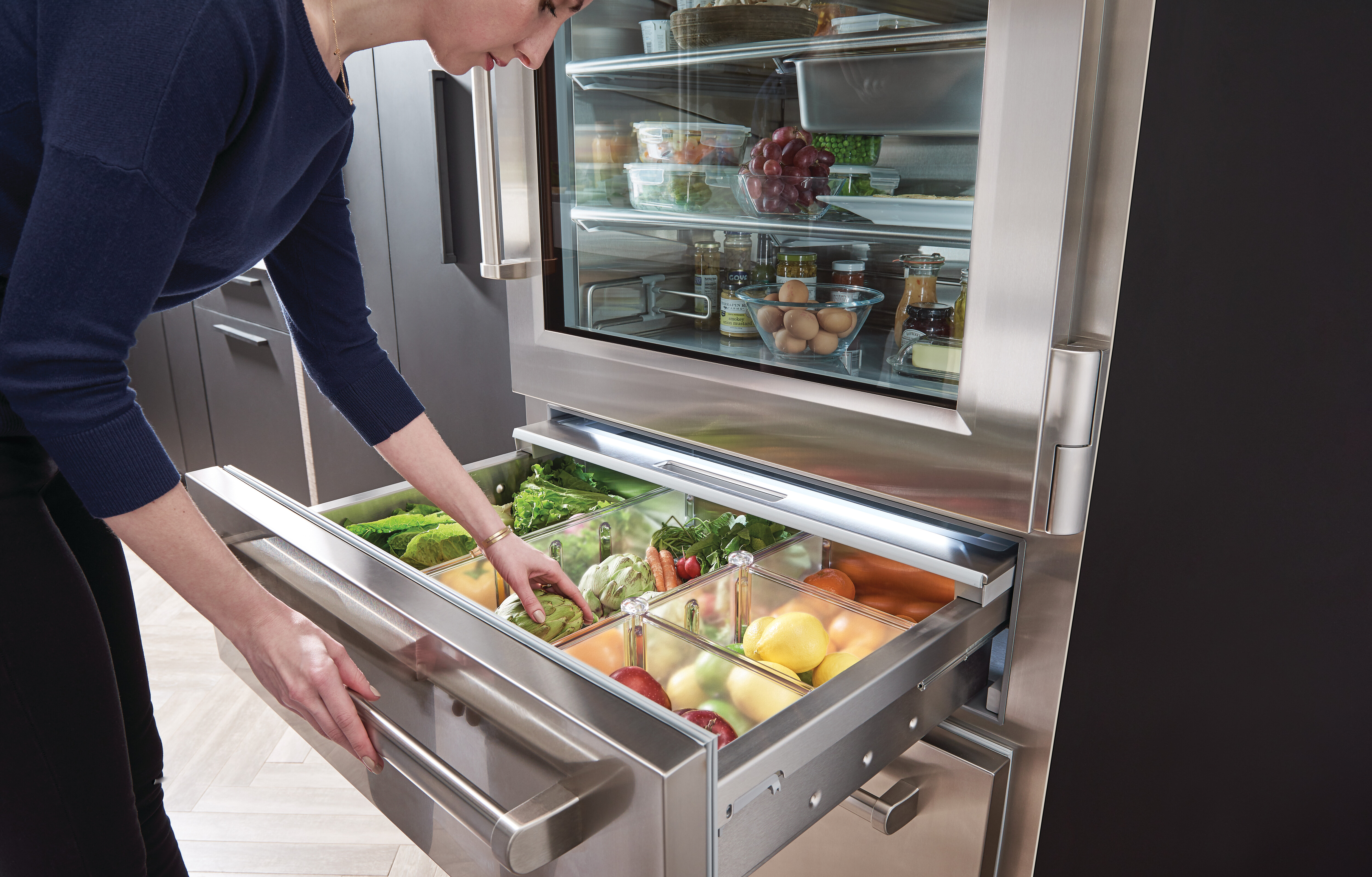 Woman grabbing produce from a Sub-Zero built-in refrigerator 