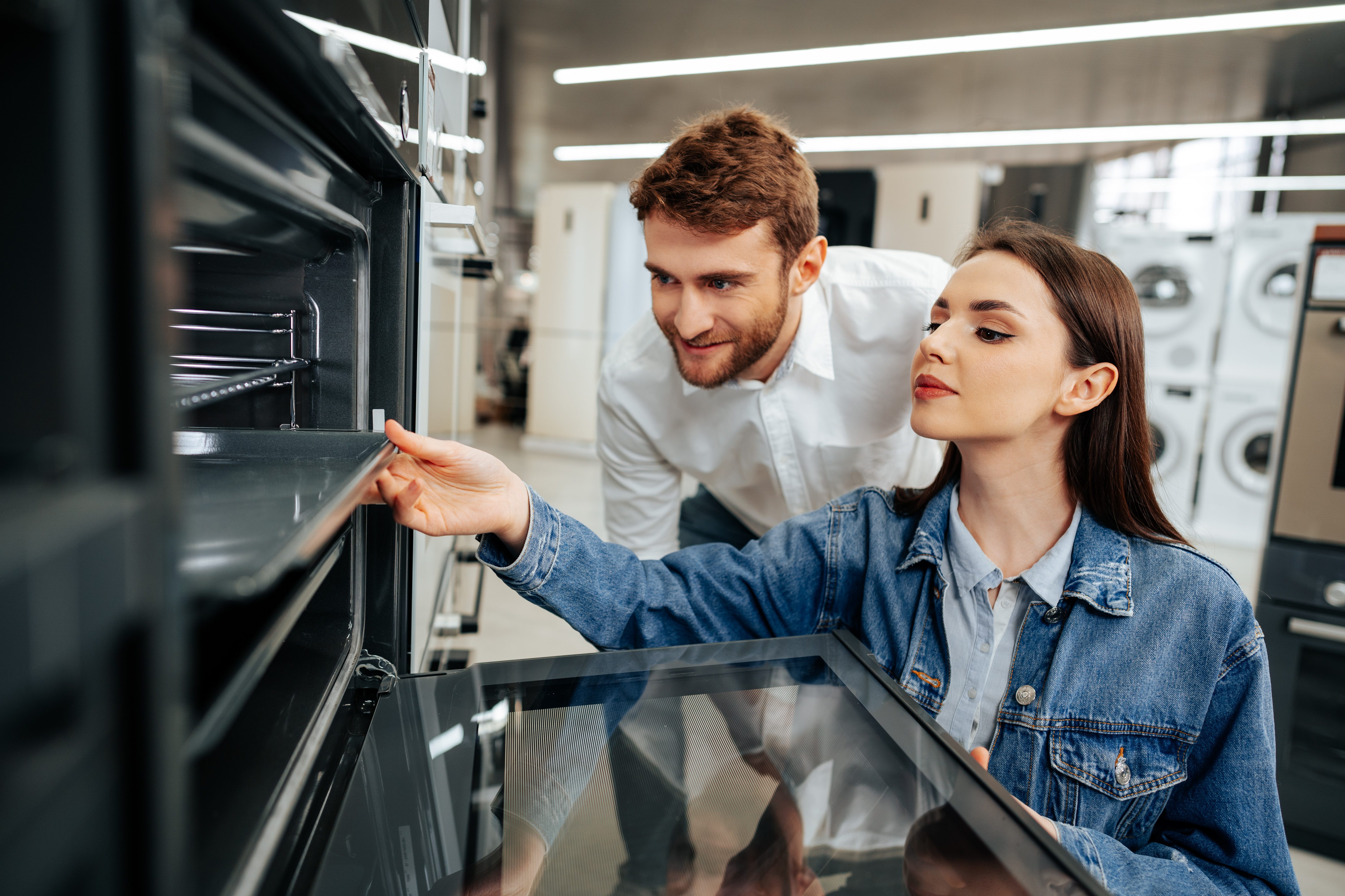 Woman and man inspecting the inside of a wall oven 