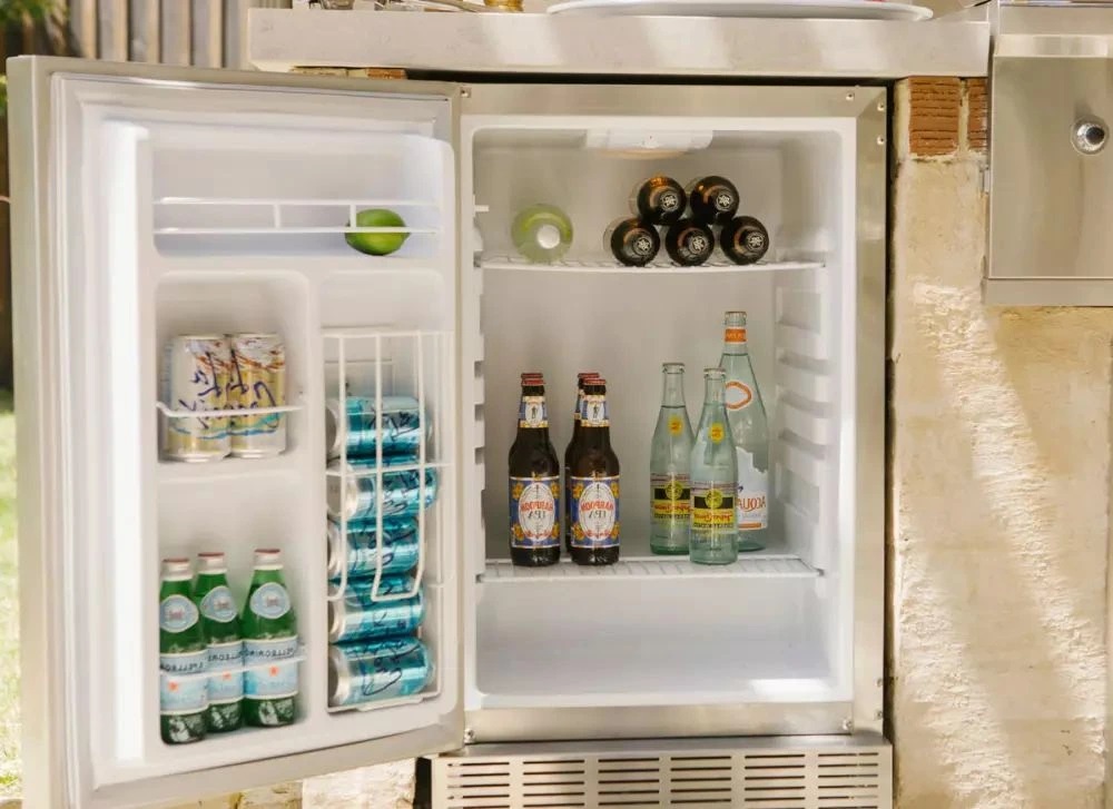 A Coyote CBIR-L outdoor refrigerator with its door open full of beverages 
