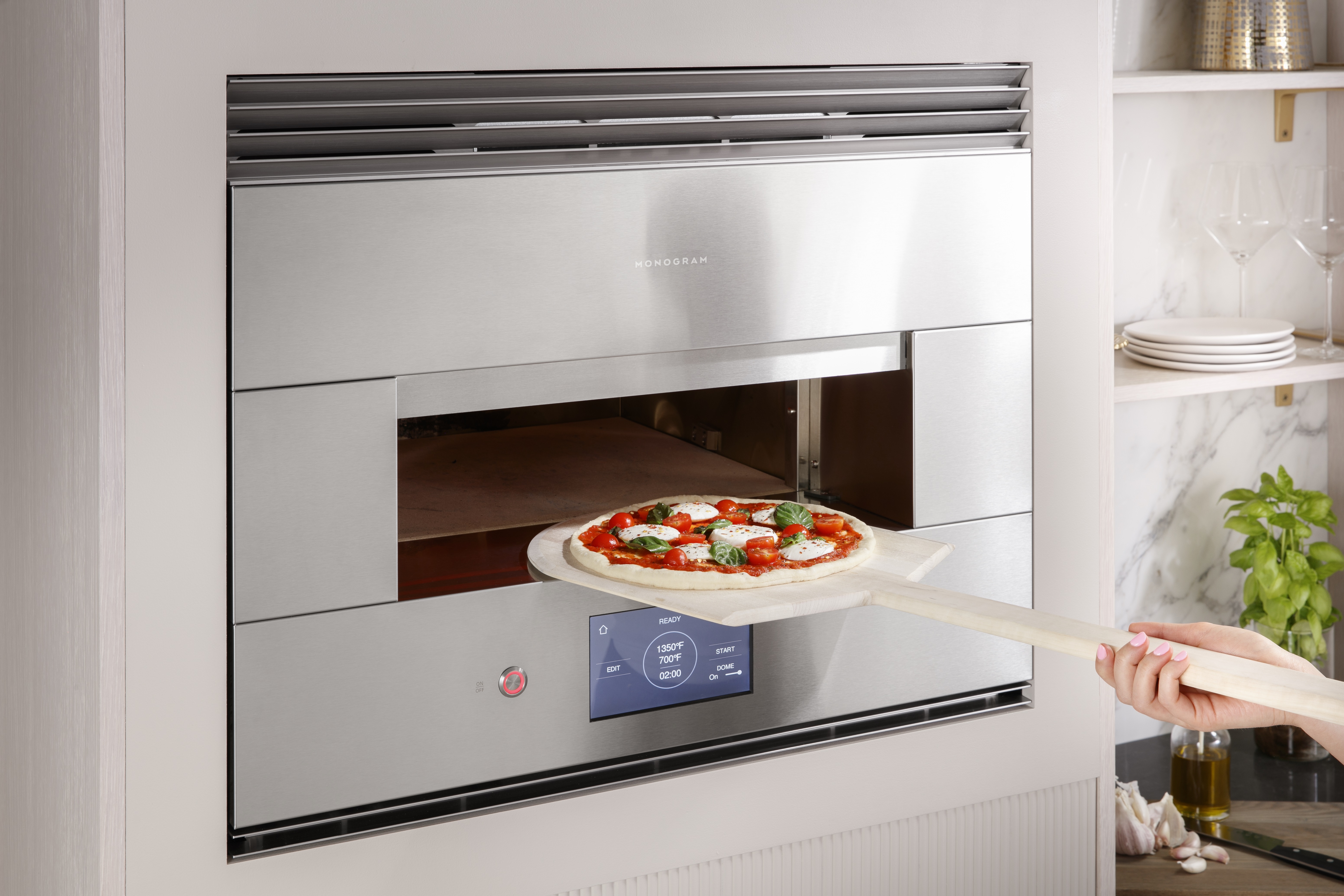A pizza going into a Monogram ZEP30FRSS 30” electric hearth 