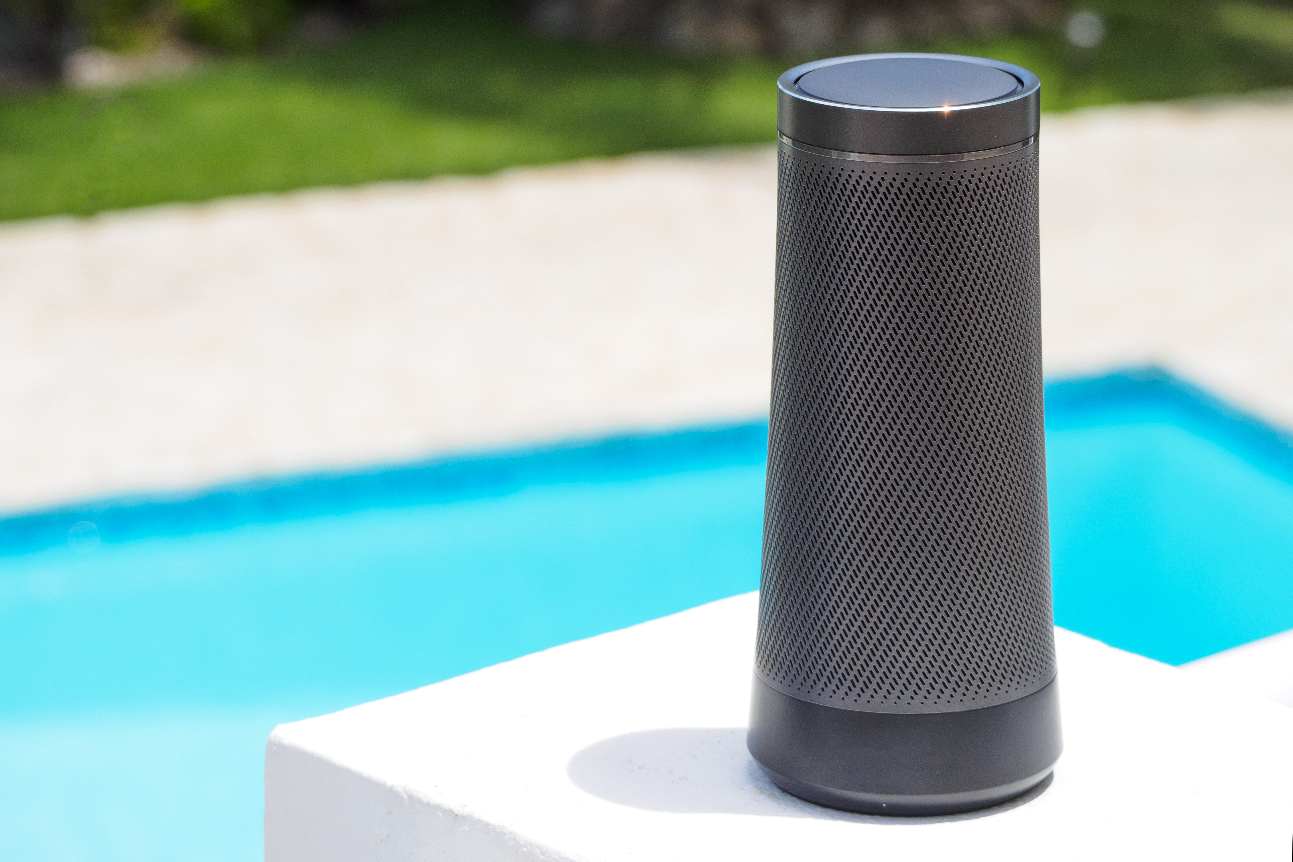 A wireless speaker shown outside next to a pool 