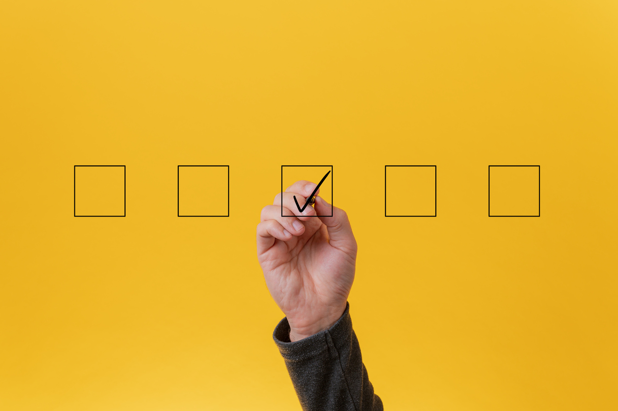 hand checking off boxes against a yellow background 