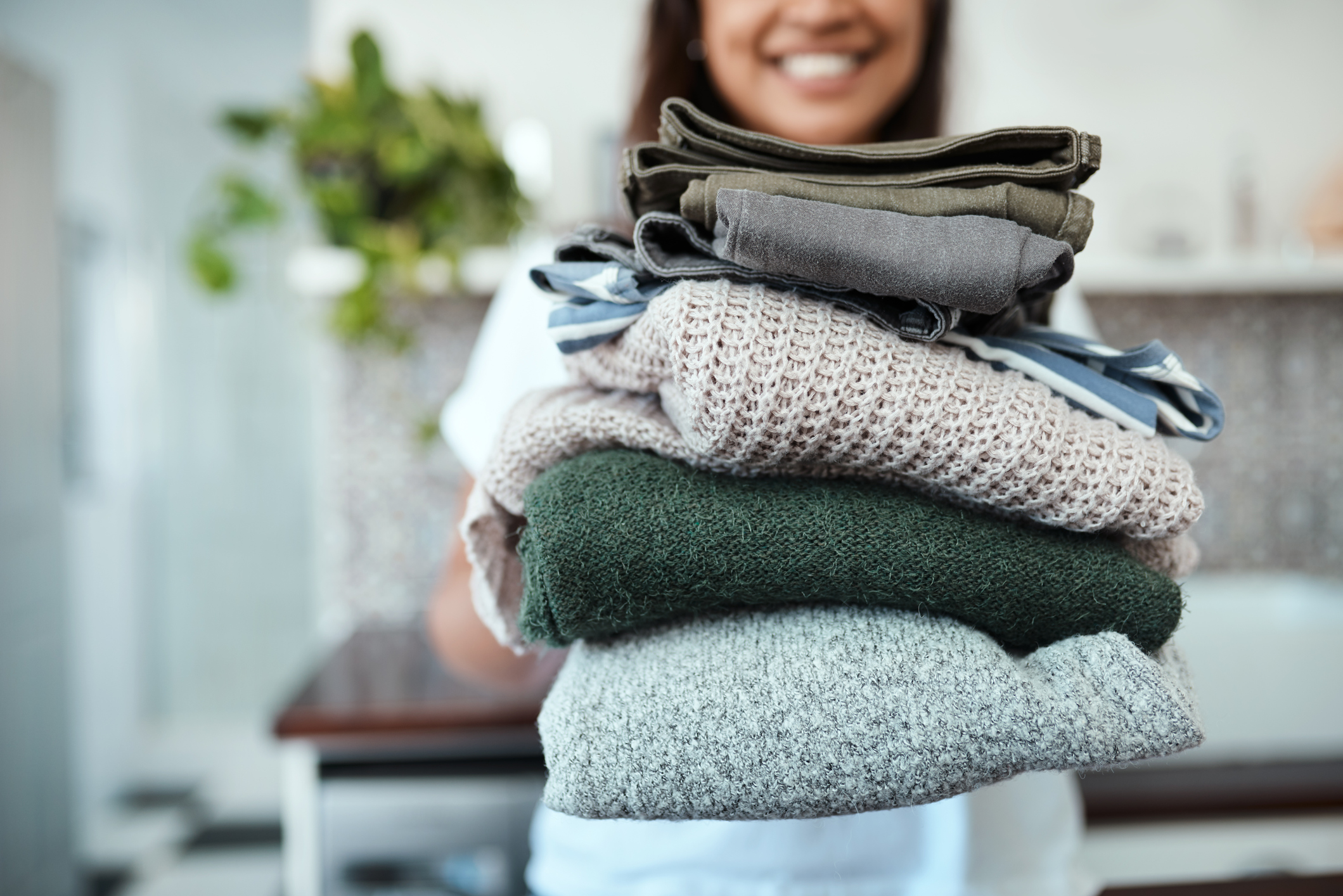 woman holding a stack of clean laundry 