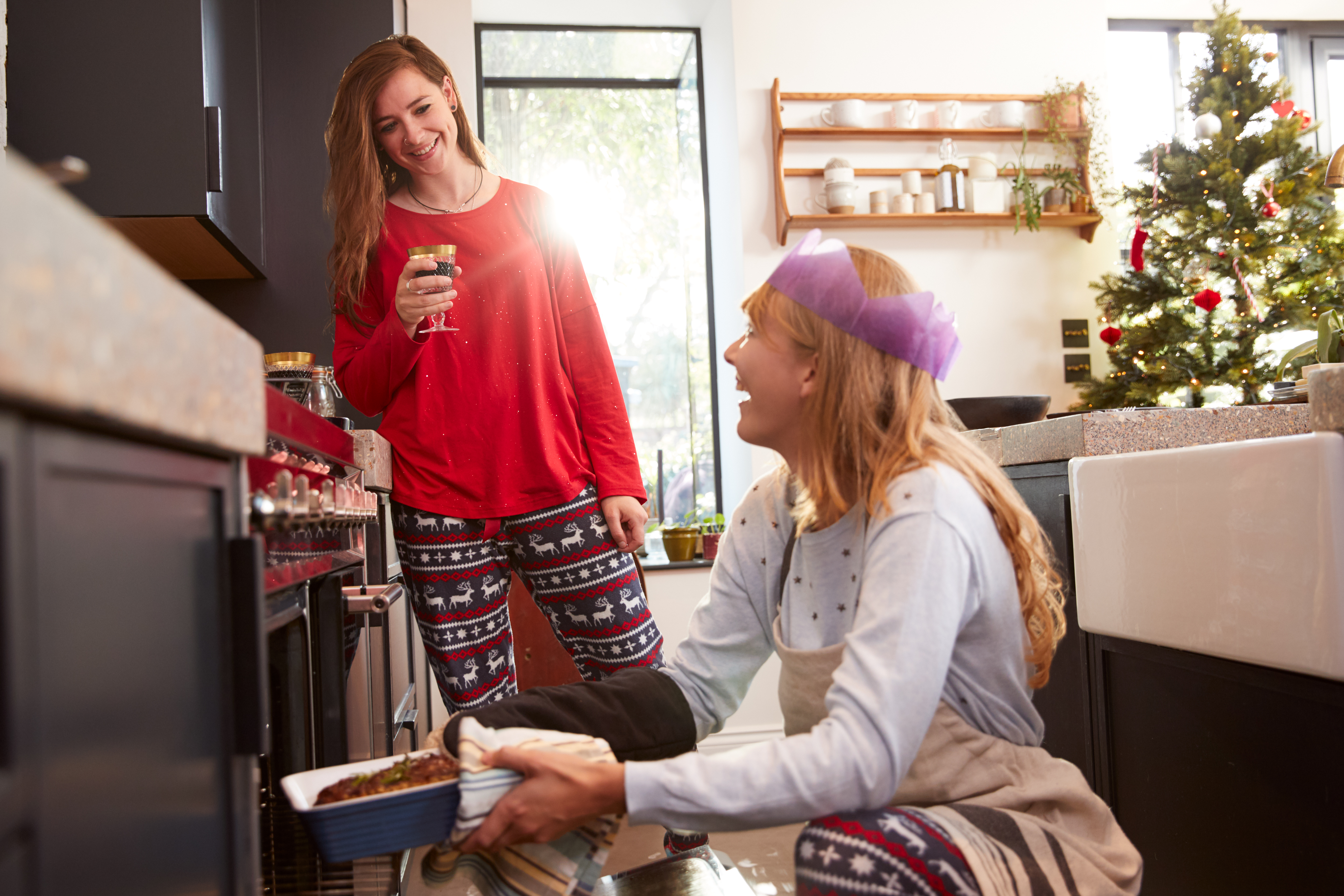 two women smiling taking bread out of the oven