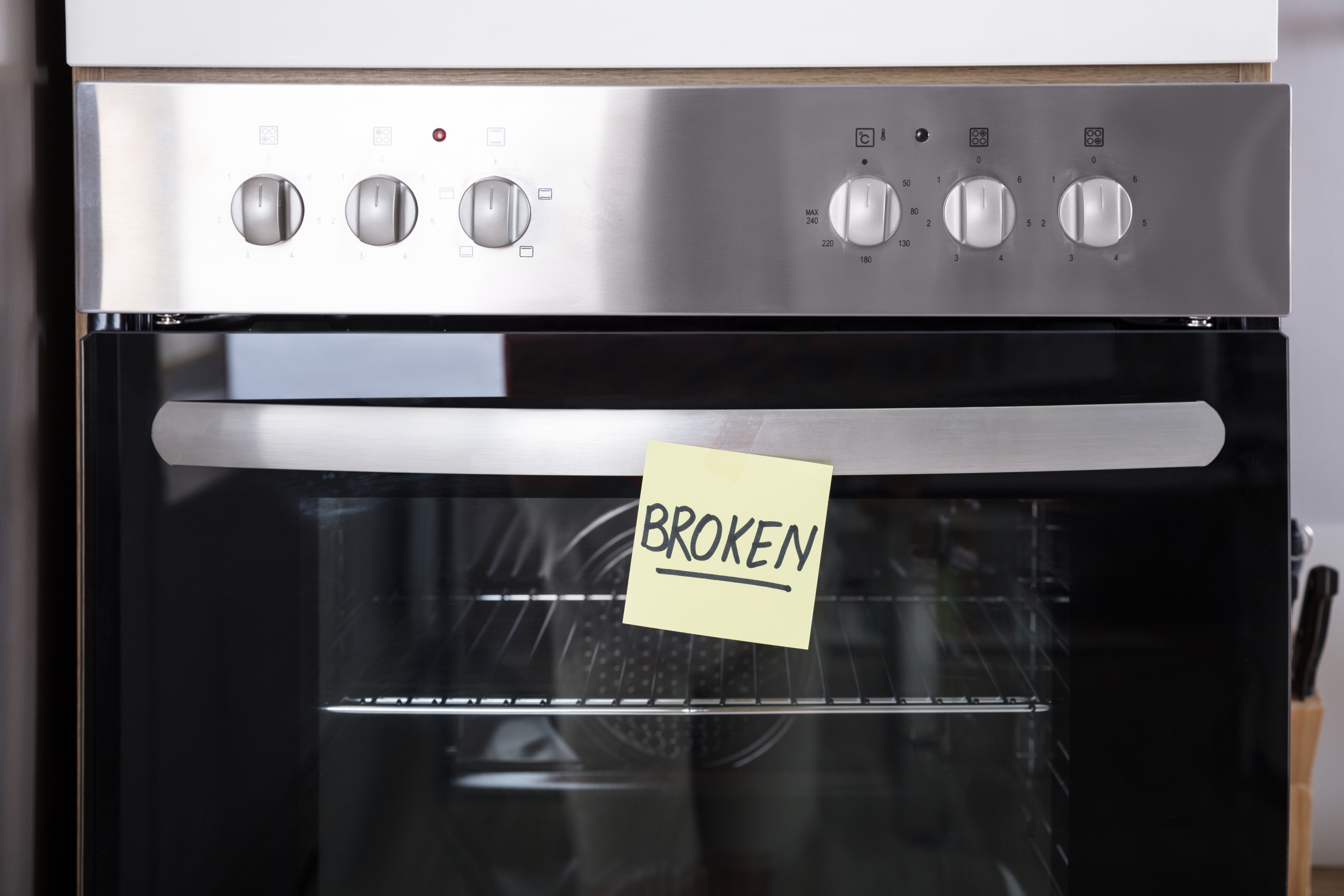 A wall oven with a sticky note saying broken 