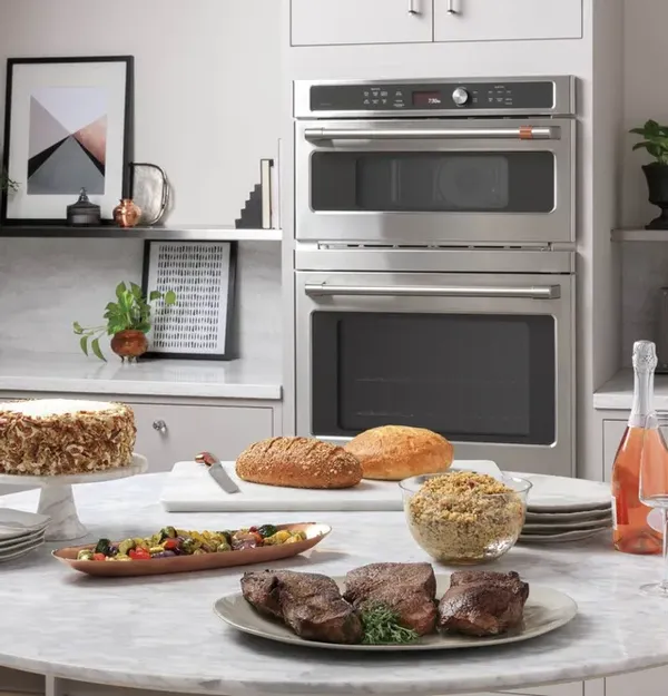 The Cafe CTC912P2NS1 microwave oven in the background with a variety of food on a counter