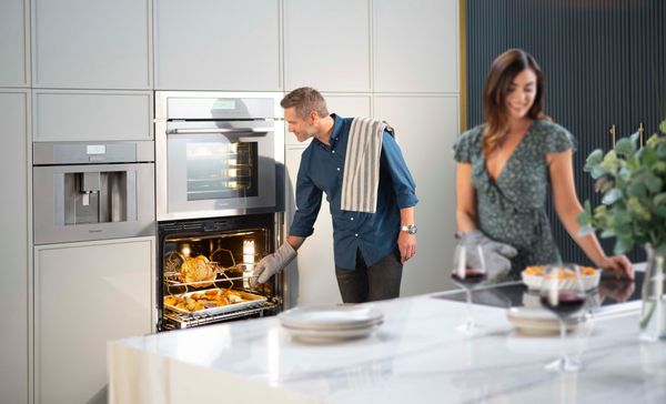 couple cook in modern kitchen with Thermador double oven