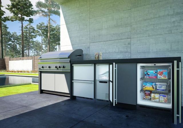 view of a modern outdoor kitchen with an opened outdoor refrigerator and ice maker