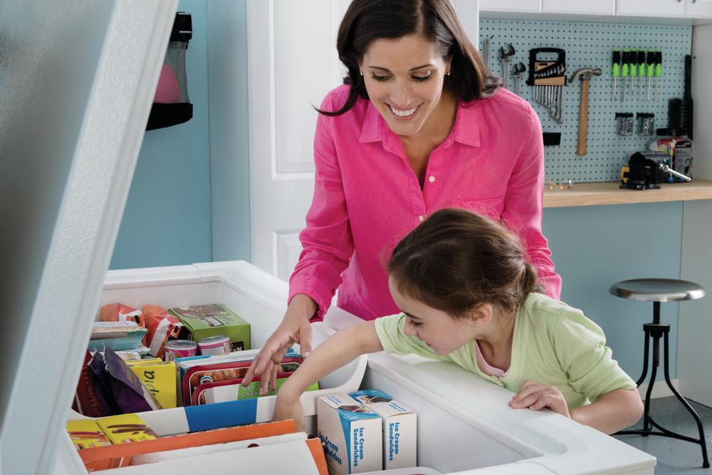 smiling mother helps daughter retrieve food from Frigidaire chest freezer