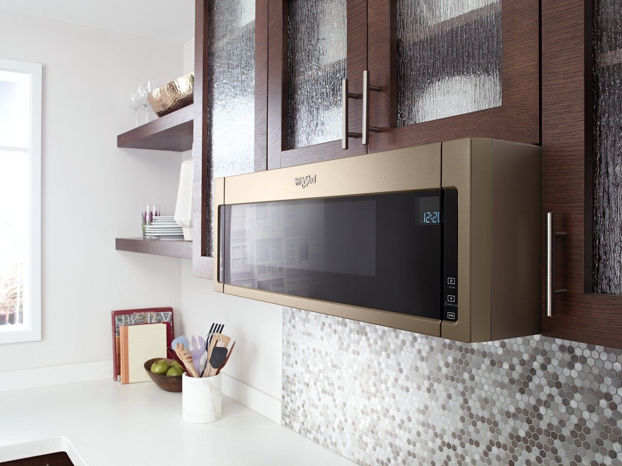 The Whirlpool wml75011hn over the range microwave in a gold finish shown over a range 