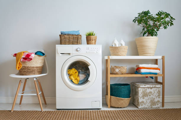 small washer with a load of laundry inside and a clothes basket beside it