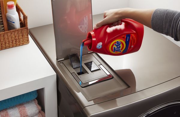 hand pours in Tide liquid detergent in dispenser of Whirlpool washer-dryer combo